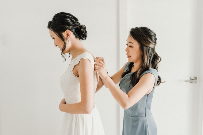 Bridesmaid helping bride get dressed.